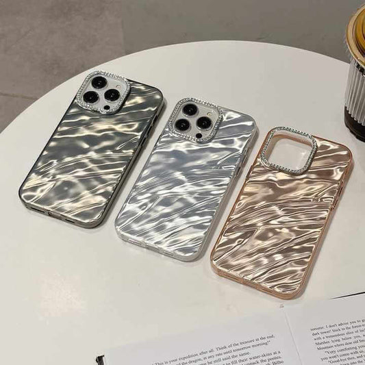 Three ResinAura mobile covers in silver, grey, and rose gold on a table, showcasing unique resin patterns and stylish design.